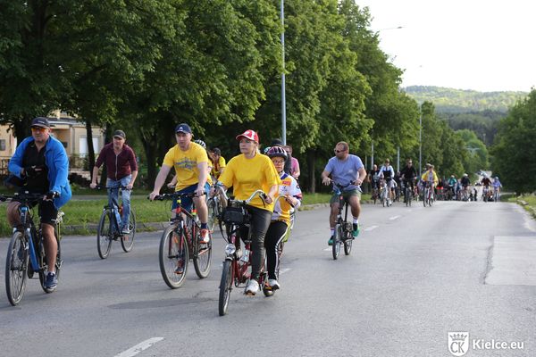 Grupa rowerzystów jedzie ulicą. Na pierwszym planie dwie osoby ubrane w żółte koszulki.