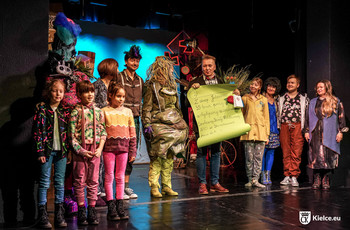 Grupa aktorów i dzieci na scenie Teatru Lalki i Aktora