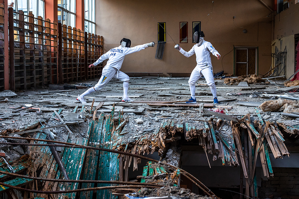 Zdjęcie Mykoła Synelnikowa z Charkowa, dwóch szermierzy trenujących w zniszczonej hali