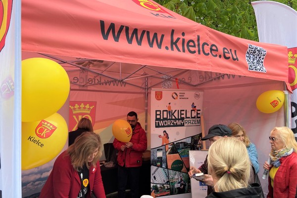 Namiot z adresem strony internetowej www.kielce.eu, przy namiocie kilka osób, żółte balony z herbem Miasta