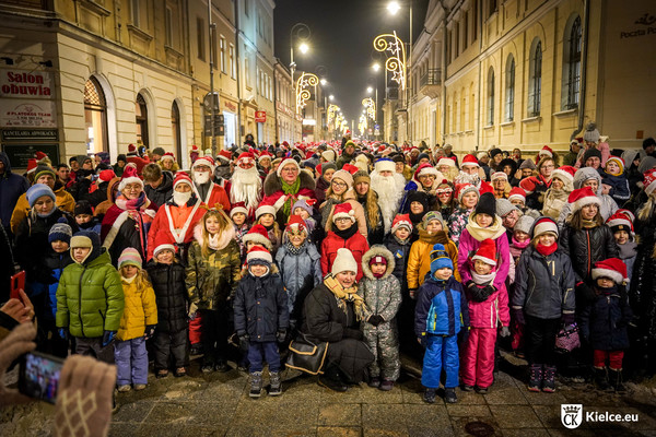 Grupa dzieci i dorosłych na ulicy Sienkiewicza, część osób przebrana jest w kostiumy Świętego Mikołaja