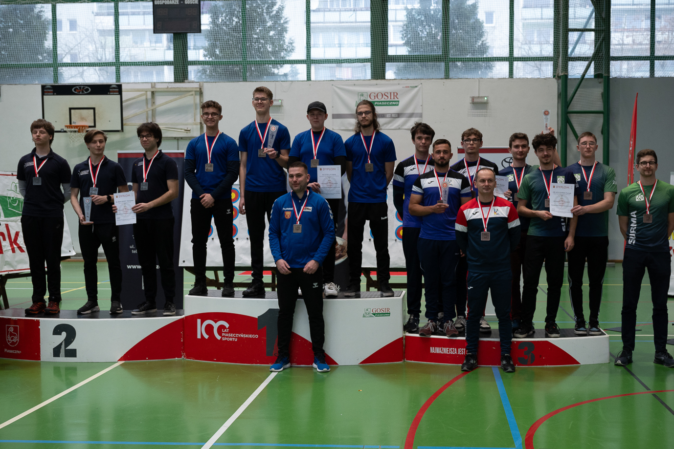 Kilkunastu łuczników na podium po odebraniu medali i dyplomów w zawodach mistrzostw Polski w łucznictwie
