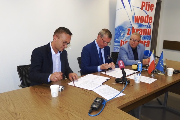 zdjęcie przedstawia podpisanie umowy na realizację inwestycji. Dokument podpisują prezes Wodociągów Kieleckich, Henryk Milcarz oraz prezes firmy "Hydroconster" Łukasz Gajda.