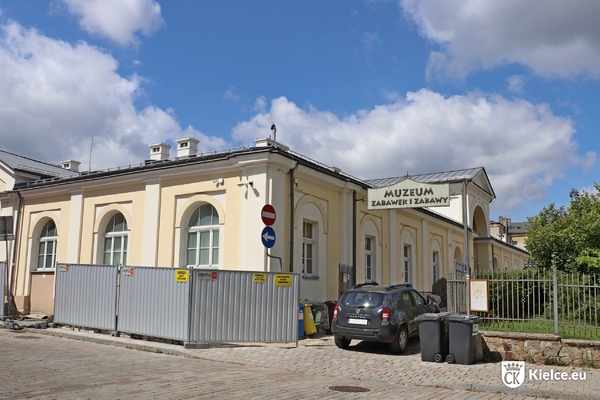 Budynek Muzeum Zabawek i Zabawy, wejście od ul. Ewangelickiej, przy budynku stoi ogrodzenie, na pierwszym planie zaparkowany samochód