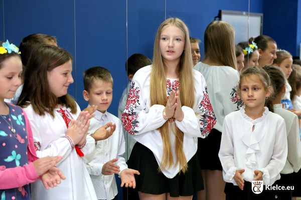 Trzy dziewczynki i chłopiec ubrani w białe bluzki z haftami nawiązującymi do ukraińskich strojów ludowych.