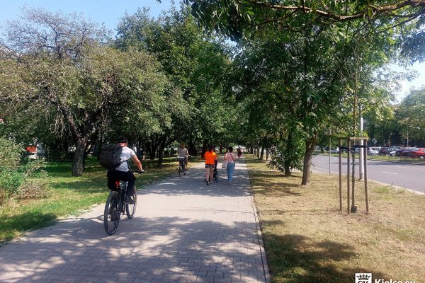 Chodnik przy ulicy Sandomierskiej, na rowerach jadą dwie osoby, dwie osoby spacerują z dziecięcym wózkiem