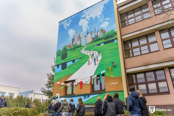 Mural na ścianie I LO, przed nim grupa młodych ludzi