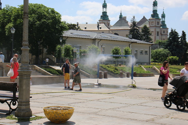 Kurtyna wodna na Placu Artystów, obok przechodzi kilka osób.
