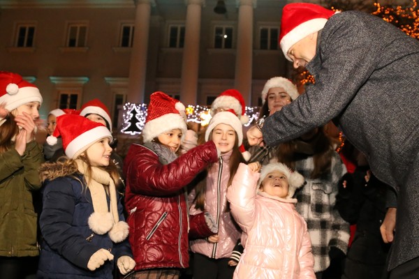 Prezydent Kielc Bogdan Wenta wraz z grupą dzieci włącza lampki na miejskiej choince