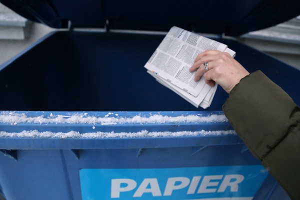Śmieci wyrzucane do niebieskiego pojemnika na papier.